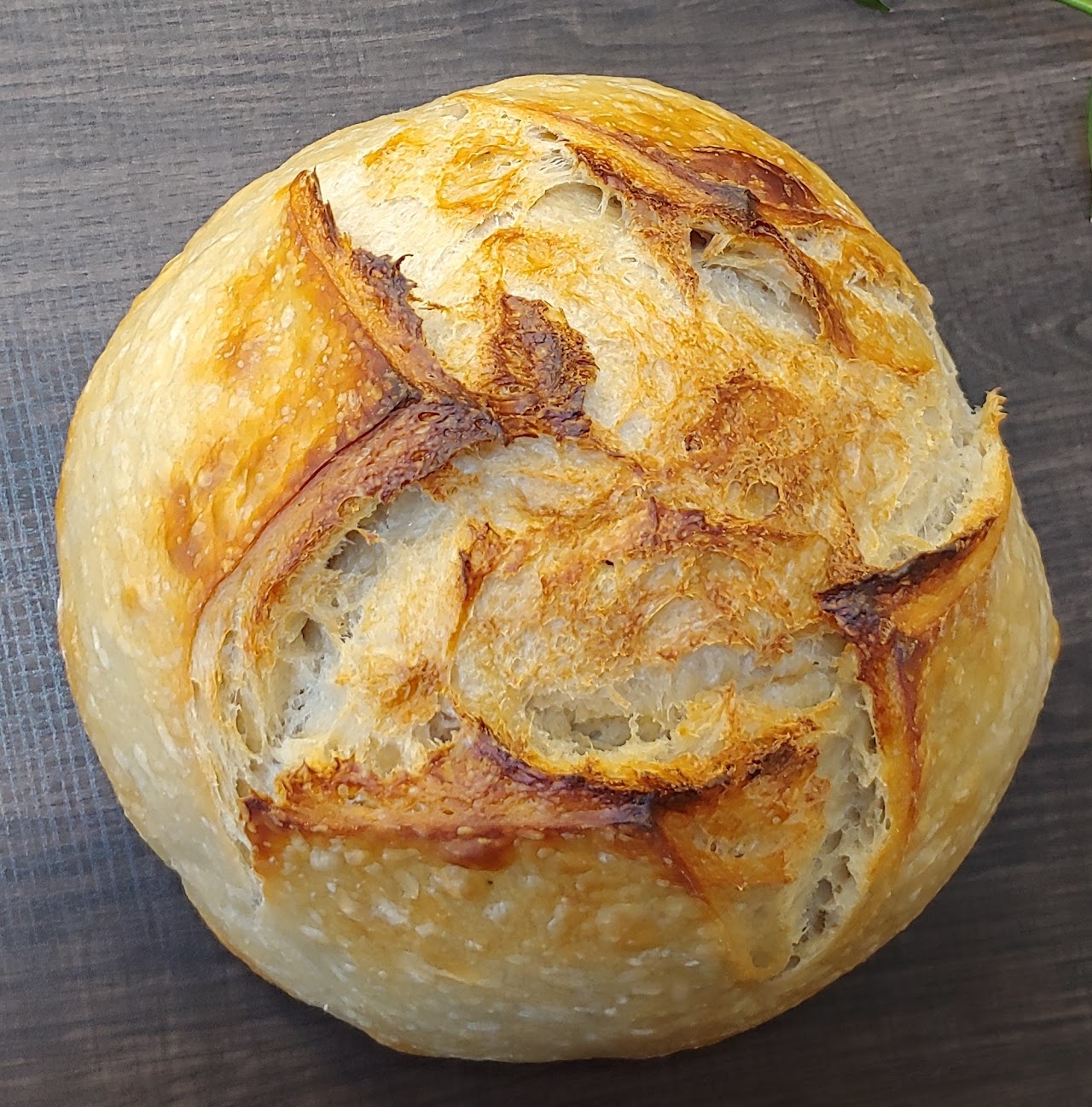A golden round sourdough loaf with crisp scored crust